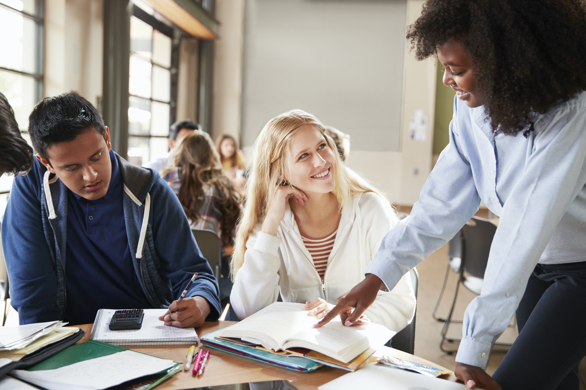 Group Of High School Students With Female Teacher Working At Desk